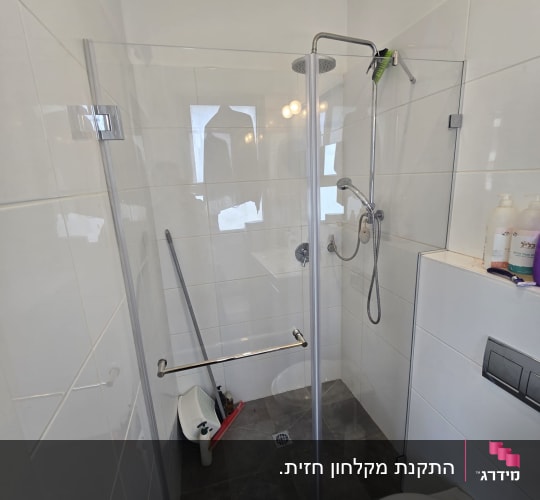 מקלחון זכוכית פינתי מותקן בחדר רחצה מרוצף ומחופה אריחים